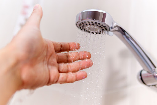 A hand testing the water pressure coming from a showerhead.