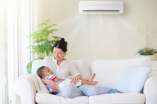 Mom holding son while laying on couch under mini split AC