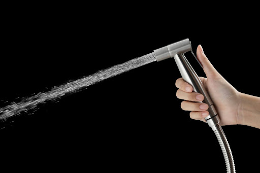 Hand holding kitchen sprayer shooting out water