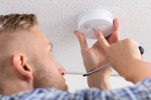 Neighborhood electrician checking smoke detector.